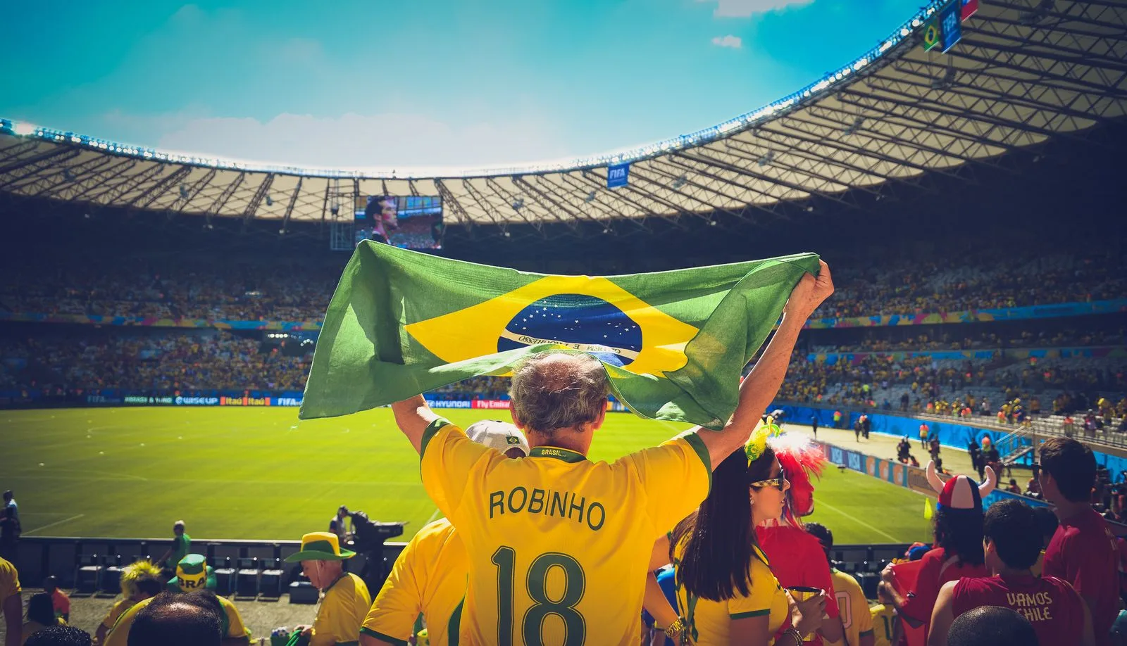 A Brazil supporter in a yellow shirt holds up the national flag in a packed stadium, as Brazil beat Scotland 3-0 to top World Cup 2026 Group C in Miami on June 24